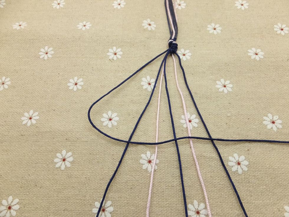 Now pick up the outermost cord on the left side (show here in dark blue) and make a forward knot by creating a 4-shape over the 2nd cord.