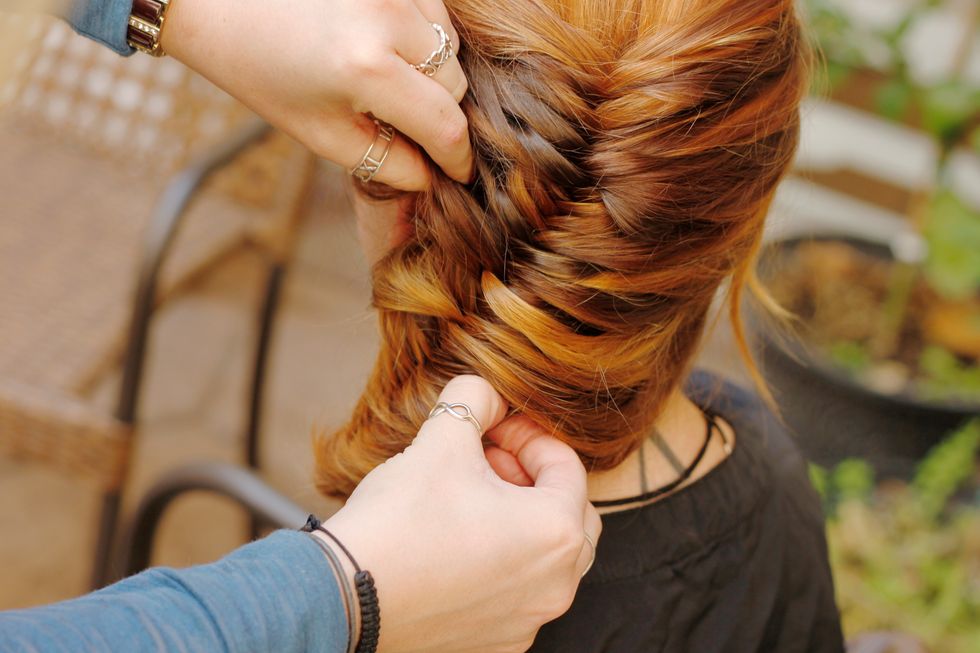 Now pinch the outside of several plaits and pull out to give it a lived-in feel and make the hair look thicker. Pin loose sections in place, and spray it with hair spray as needed.