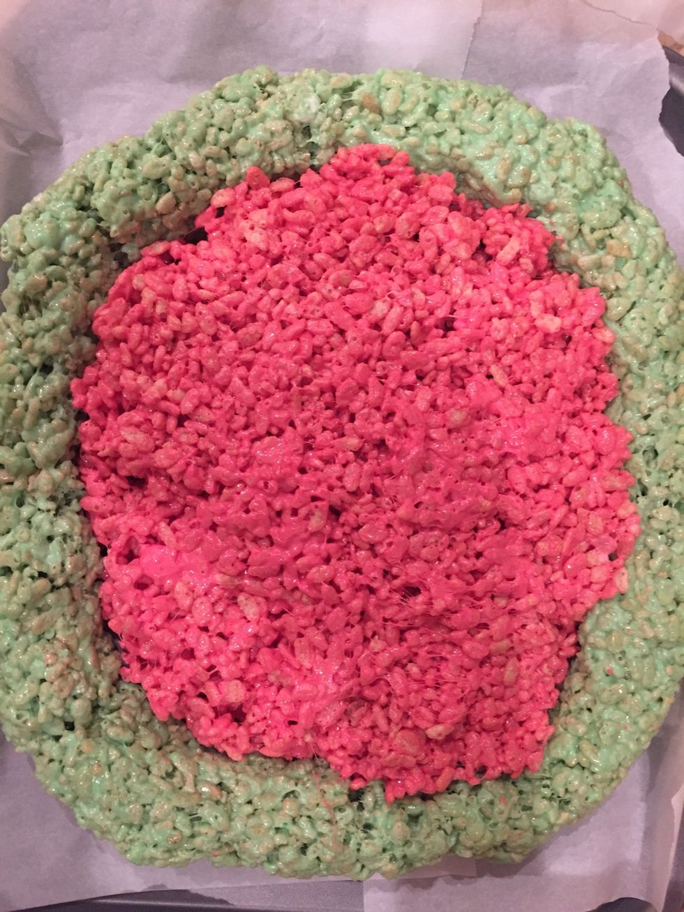 Now place the red mixture in the middle of the green rind you made. Try to spread it and level it out with your hands, by greasing them or pressing down with wax paper.