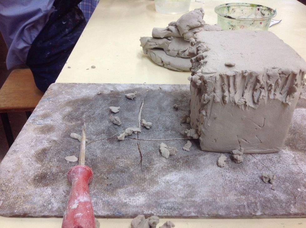 Now place the square on top of the cube and scrape clay over the crack