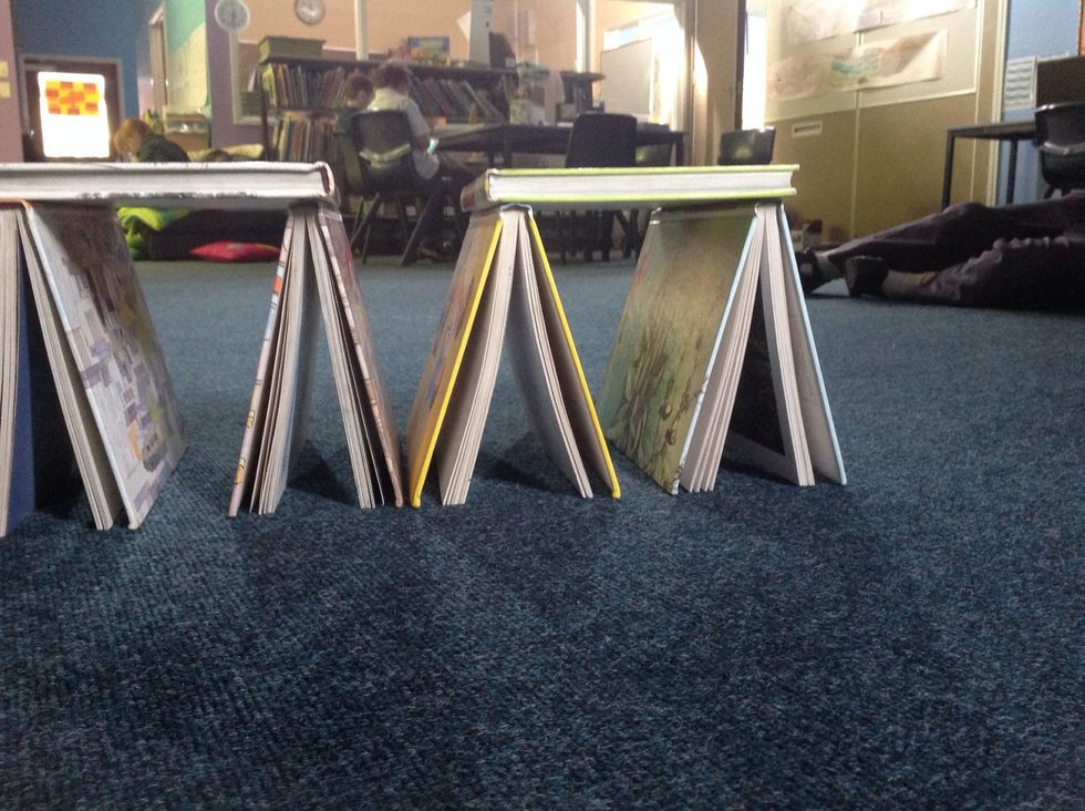 Now place two books on top of the two small towers that you have made. Make sure that the towers are near the edge where the two towers meet.