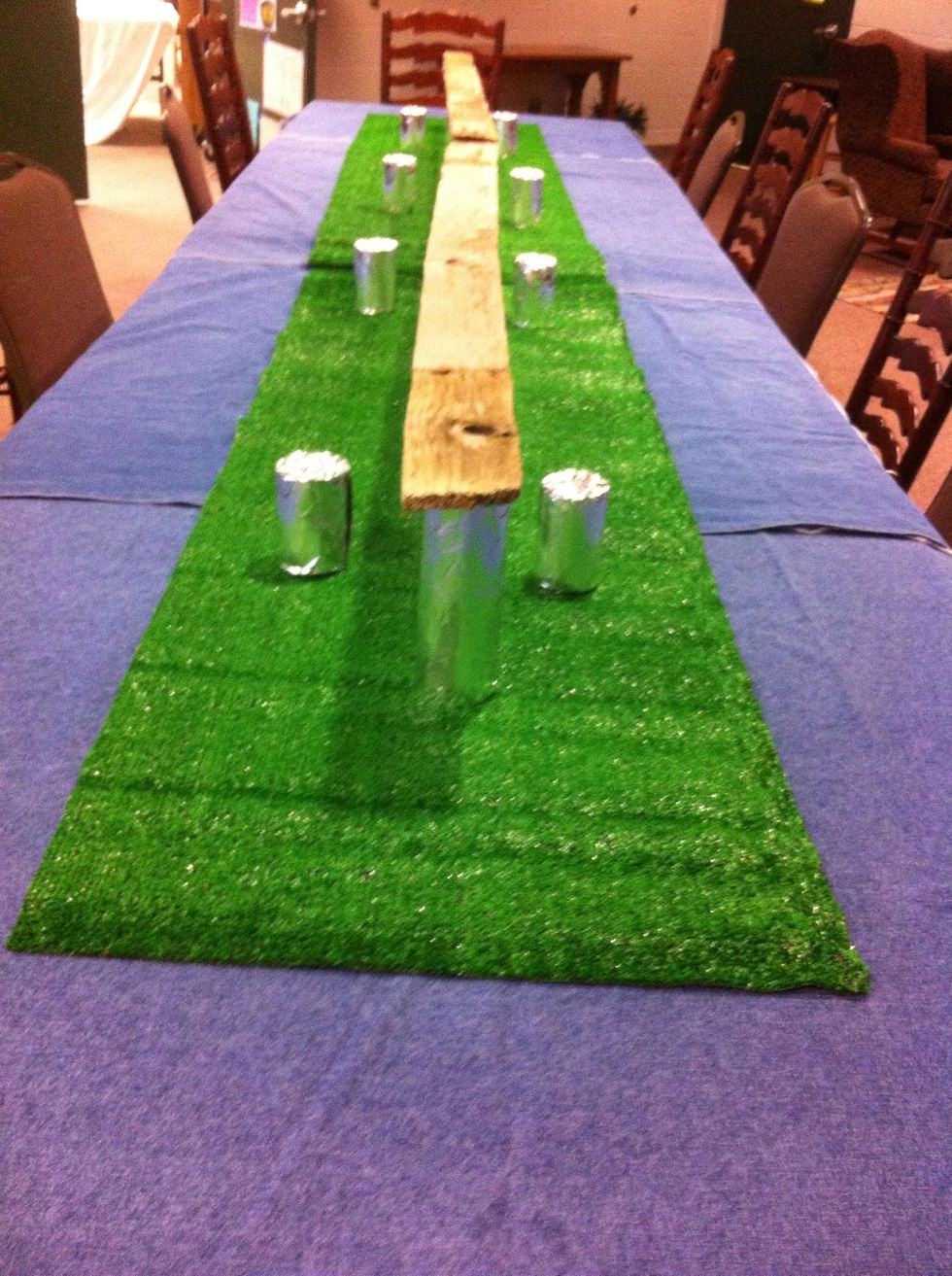 NOW. Place your double stacked cans down the middle of the table and lay one of the old fence boards on top.
