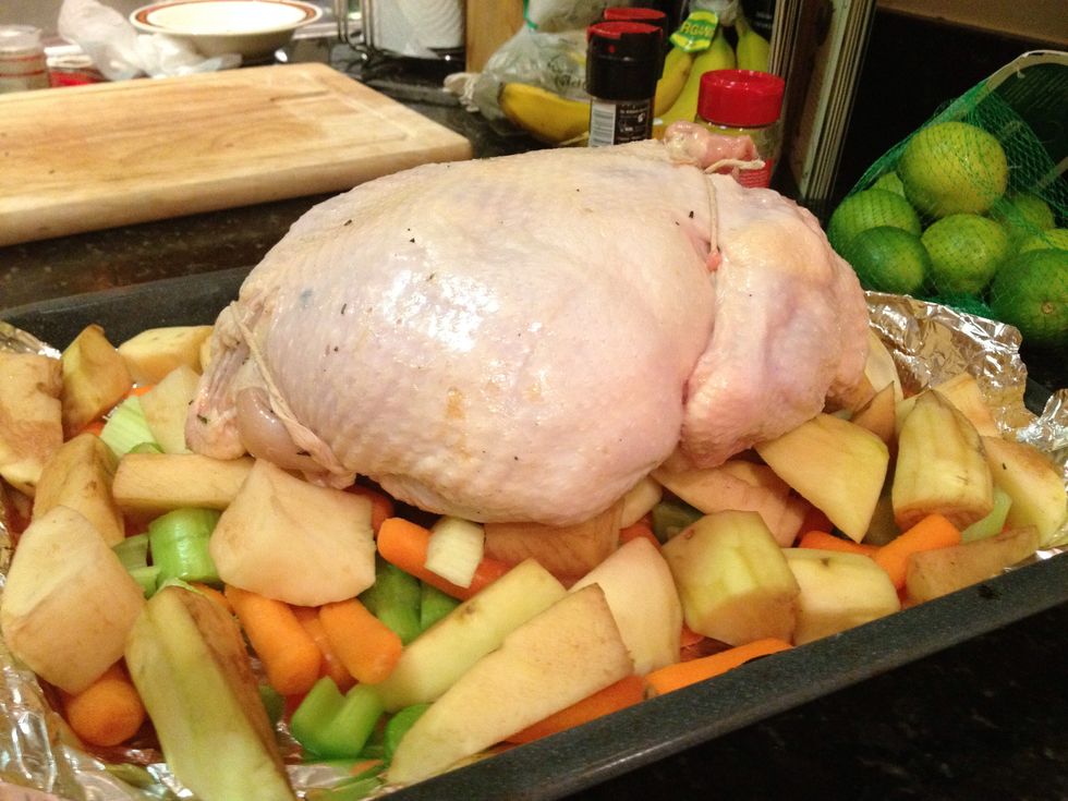 Now place your trussed chicken on top of the a roasting pan with your veggies and potatoes.