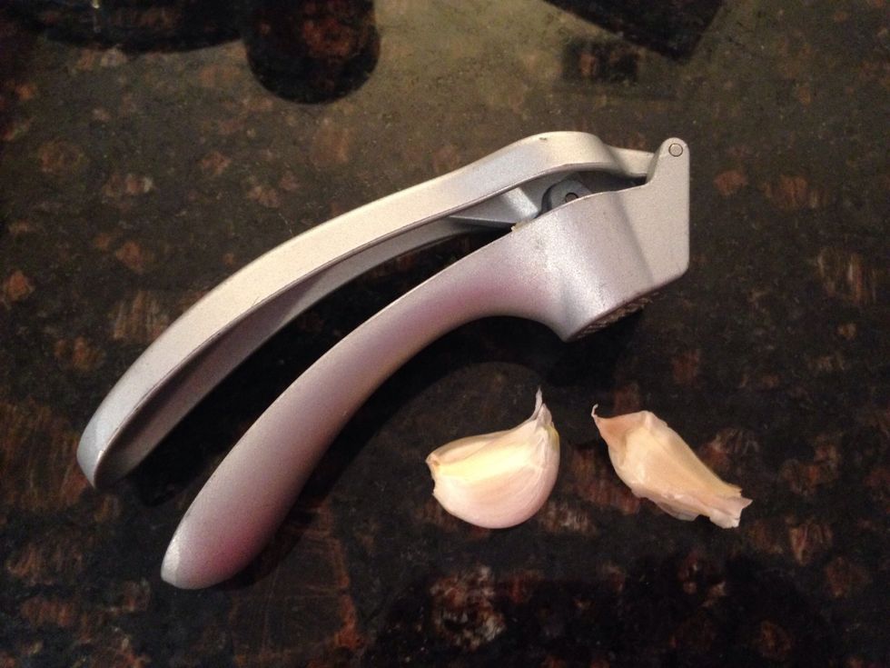 Now press 2 cloves of garlic into the stock pot.