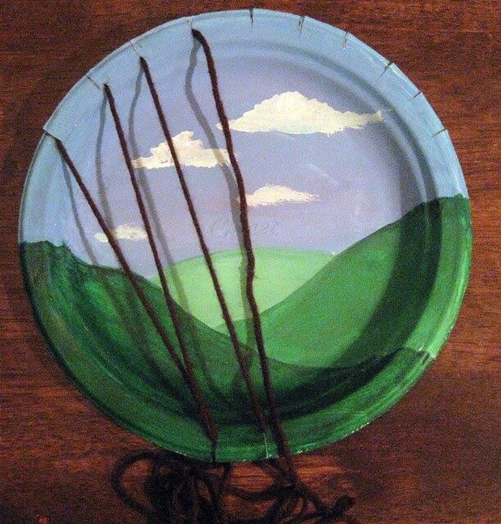 Now, pull the yarn to the bottom left notch (where you started) & push the yarn through. Staying behind the plate, move the yarn to the bottom right and pull up and out and go back up to the top.