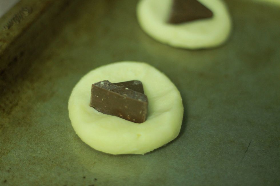 Now push a toblerone triangle into the top. If you want to be extra fancy make another ball and squish it on top to hide the chocolate surprise inside! I was lazy (and wanted more cookies) so I didn't