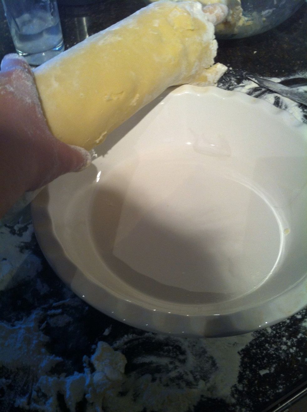 Now put the rolling pin (now with crust rolled up around it) on top of your pie plate and roll pin across dropping the crust evenly into the plate.