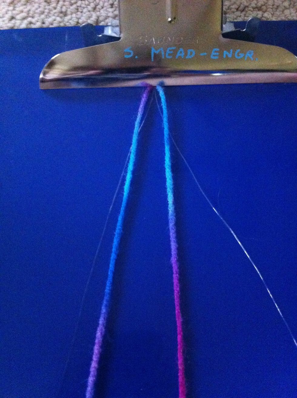 Now put the strings in the clipboard and line the strings up so that the clear ones are on the outside and the yarn is on the inside.