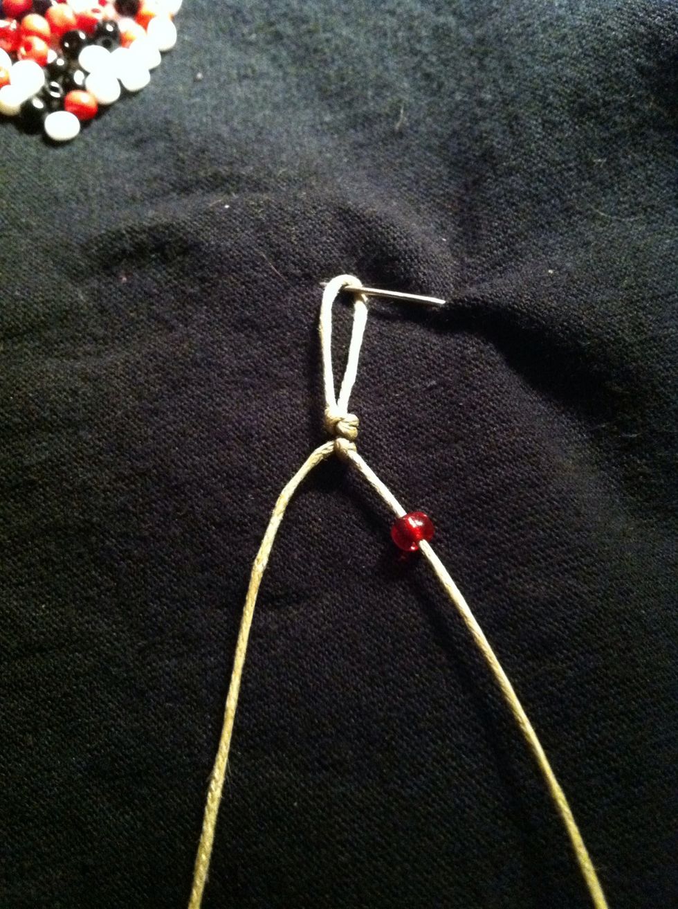 Now slide one bead up the right strand and push it snug against the knot. Hold the left strand taut.