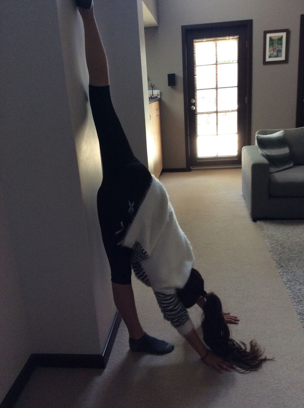 Now, stand an inch away from a blank wall and lift one leg as if you're doing a split vertically.