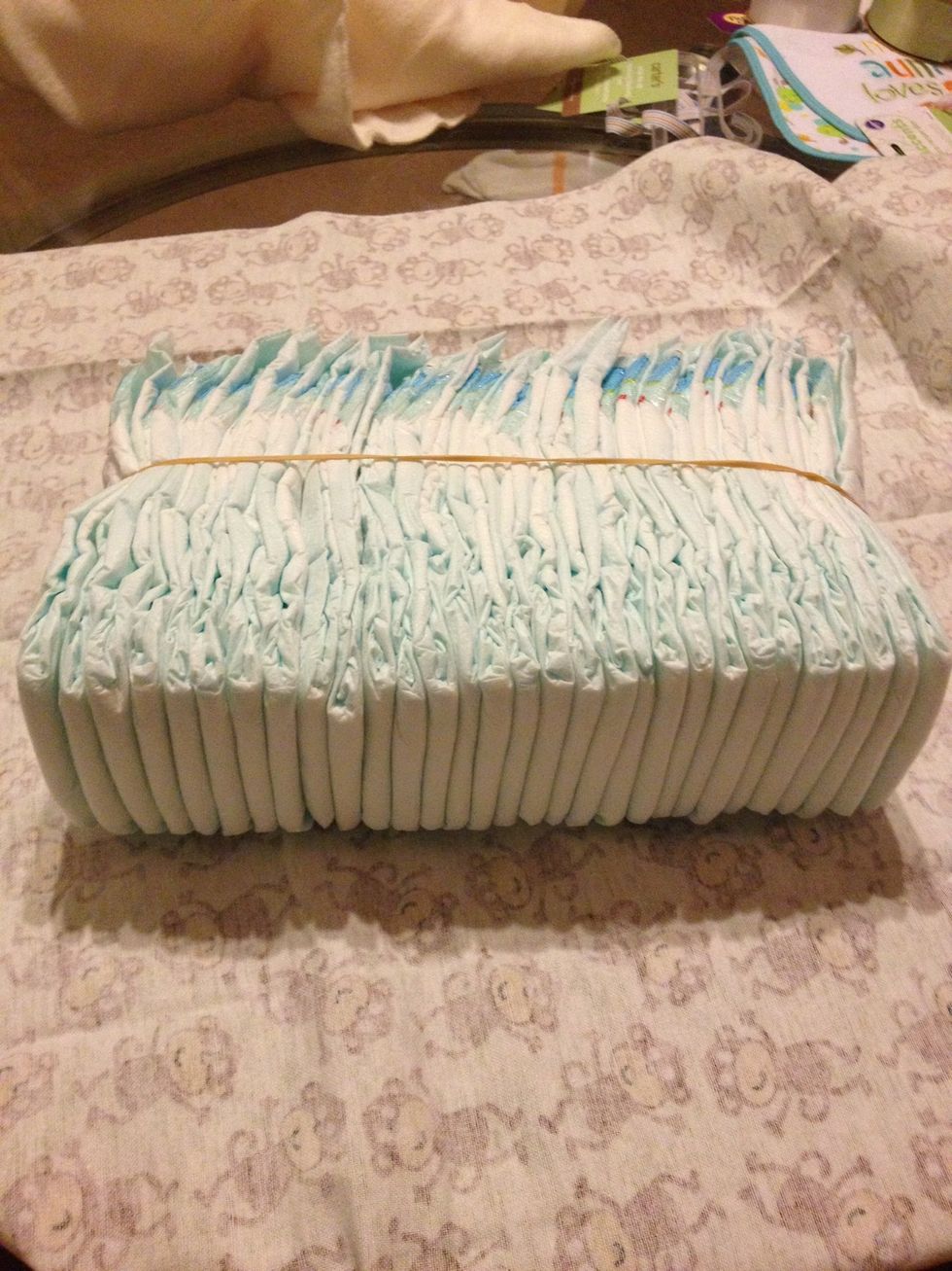 Now, take 40 diapers. There are 30 in this picture, but I added 10 more after to make 40 because it wasn't big enough. Line the diapers straight. Put a rubber band across