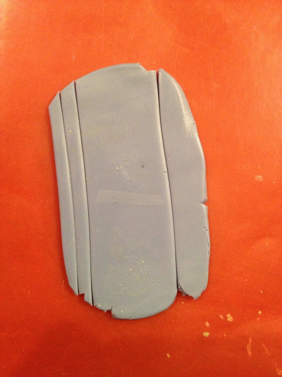 Now take a piece of blue clay and flatten it. Yes, it is blue. Believe me. It's the lamp who is guilty. Cut out a long rectangle for the pants and two stripes for the suspenders.