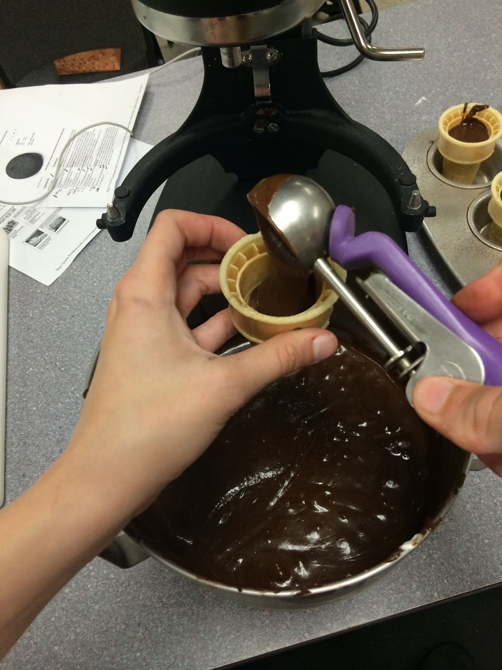 Now, take an ice cream scooper and fill your ice cream cones to one and a half to two scoops of cake batter. Do not fill them too much otherwise during baking the cake will overflow out of the cones.
