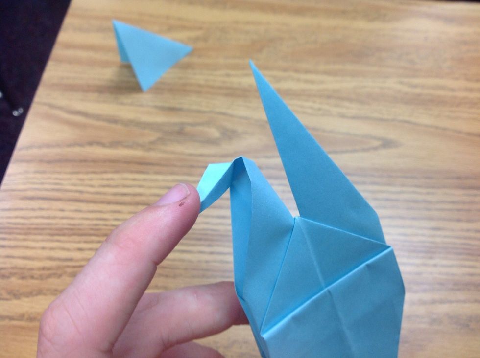 Now take one of the two top points and push it down as shown, then squeeze it together from the sides of the head to make it flat.