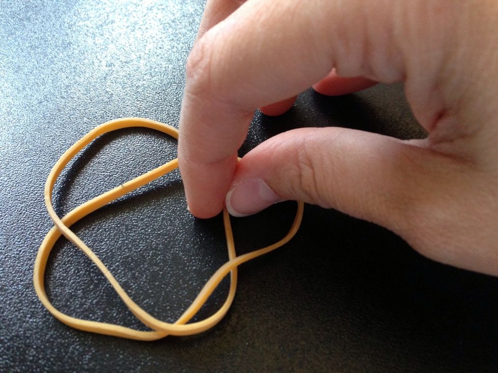 Now take the bottom rubber band and pull it through the top one halfway.