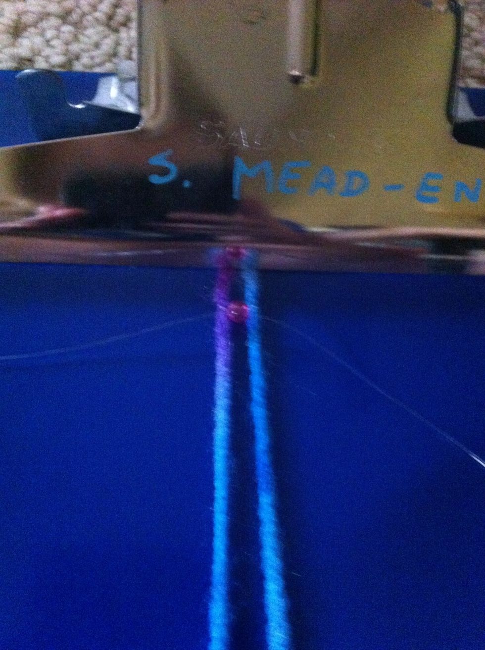 Now take the clear string on your left side and thread it through the left side of the bead and do the same to the right strand but stick it though the right side of the bead. Now pull tight.