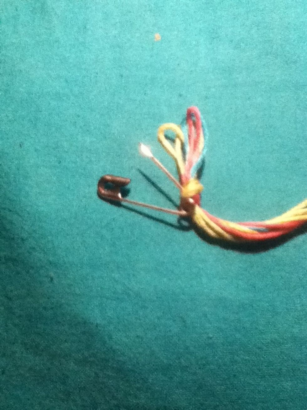 Now take the safety pin and poke it through the knot then safety pin it to some thing like a pillow or you bed