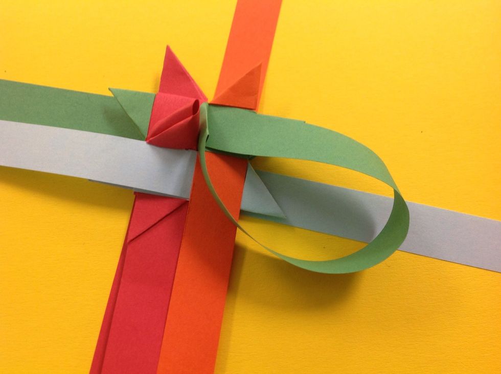 Now take the top right horizontal strip.. and fold it at a 90 degree angle towards the center of the triangle. Make a tight crease. Feed the paper into the hidden opening next to the loop.
