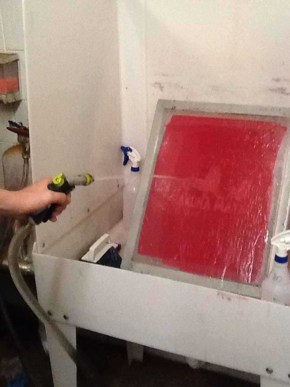 Now, take the vellum paper off the screen. Bring the screen to the sink and hose it down. Keep going until your image is fully white on the screen and there is no emulsion on the image.