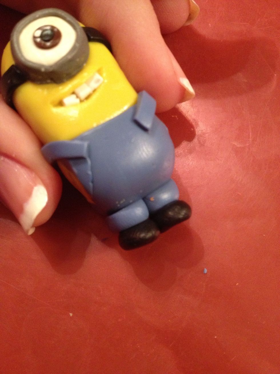 Now take two blue balls and two black balls. Flatten them a bit and your minion will get legs. Attach them.