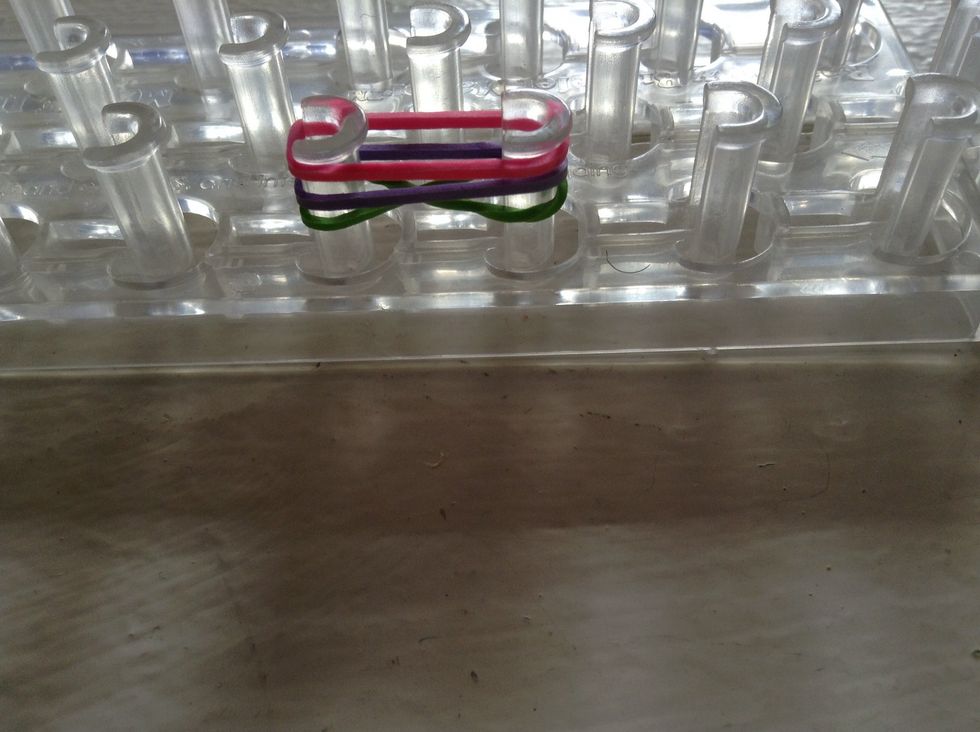 Now, take two different colored rubber bands and place them on the pegs.