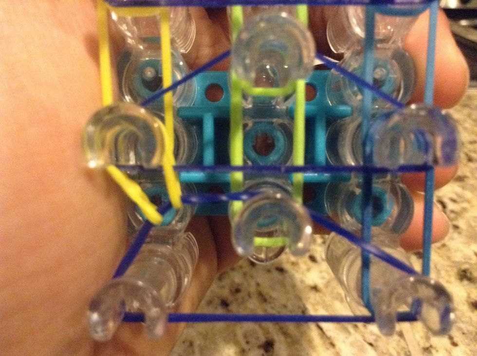 Now take your hook and take the bottom (left) rubber band and hook it to the loom hook in front of it