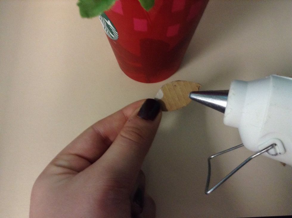 Now that your glue gun is heated, apply a small dot of glue to the smooth side of your cut out petal. Continue until all five petals form a circle. Then add one of your circles to cover the gap.