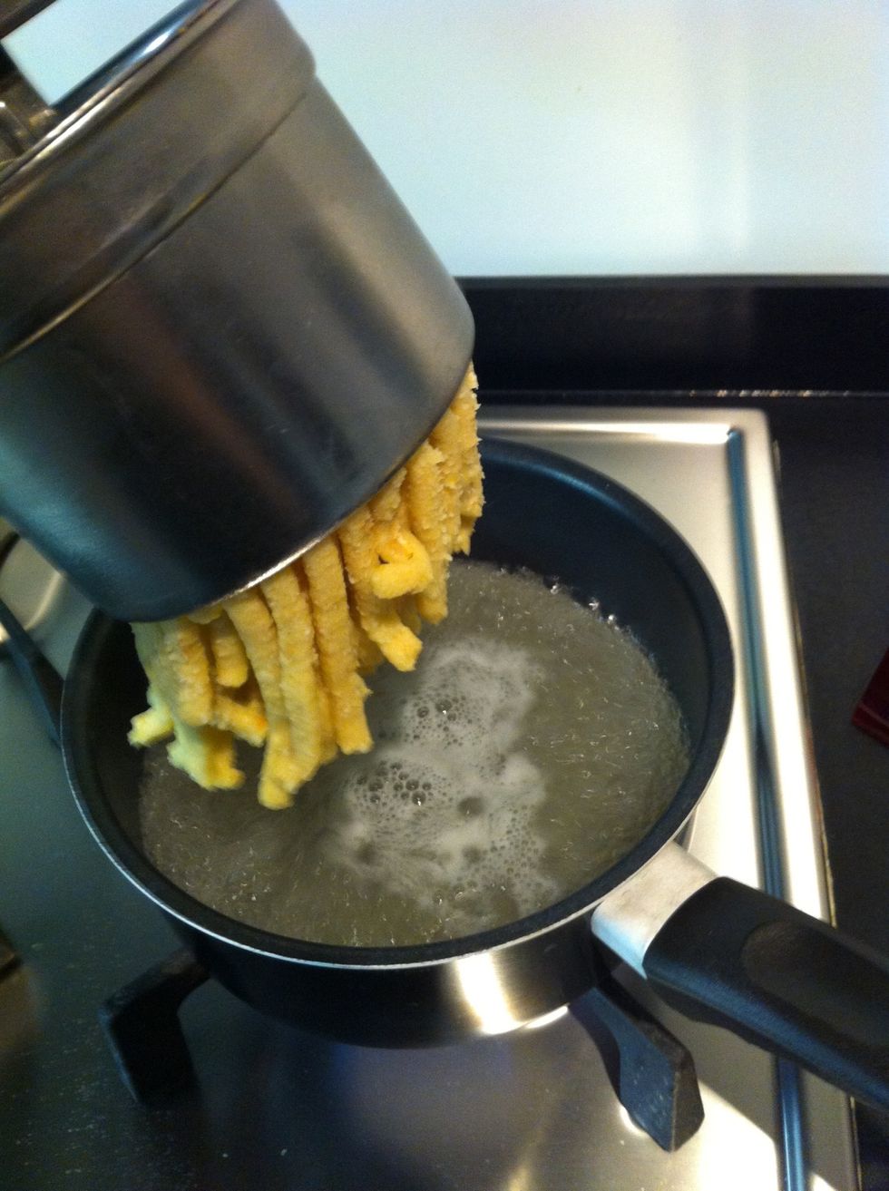 Now the broth should be boiling (make the flame faster). Call a man to help you and make him smash the mix inside the broth (cut the end with a knife)