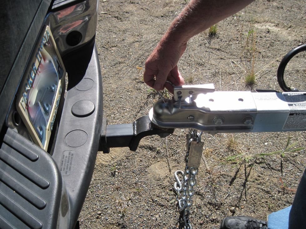 Now the little nail-sized pin goes back in the lever, to lock it in place. Flip the horseshoe-shaped lock over the pin to hold the pin in place.