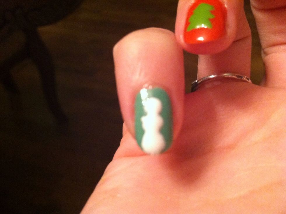 Now, the nail polish of your choice is going to be a cute snowman. Draw three white circles piled on top of each other starting with the biggest one at top of the nail and shrinking them as you go up