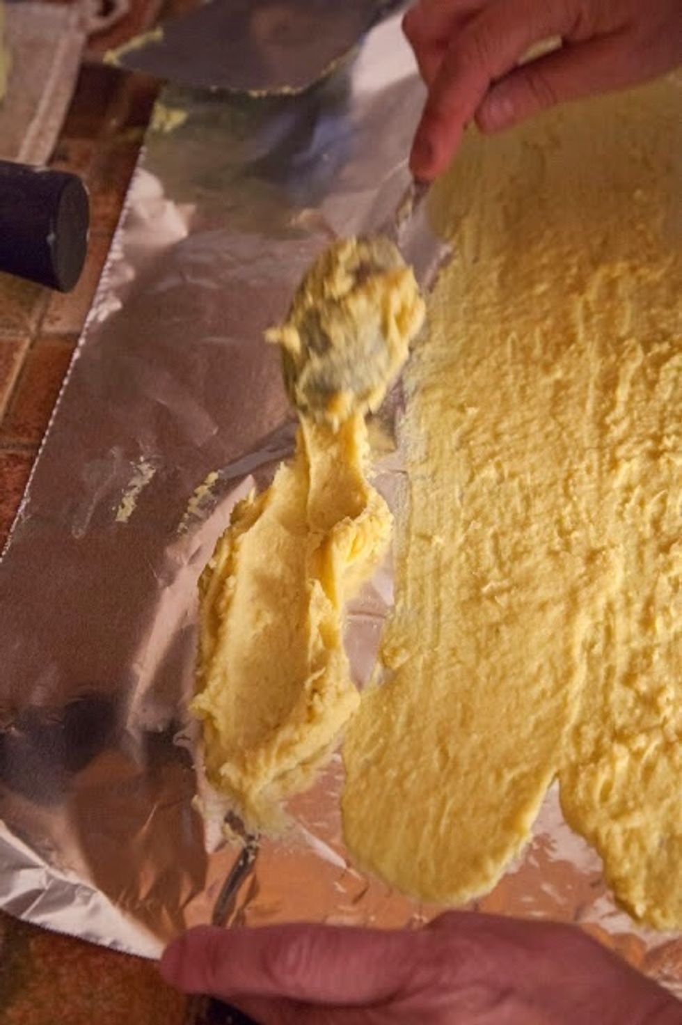 Now, this is the only tricky part where it's important to work fast, as the batter will start to firm up and set. With a spoon, drop a strip of batter along the edge of one of the sheets of tin foil.