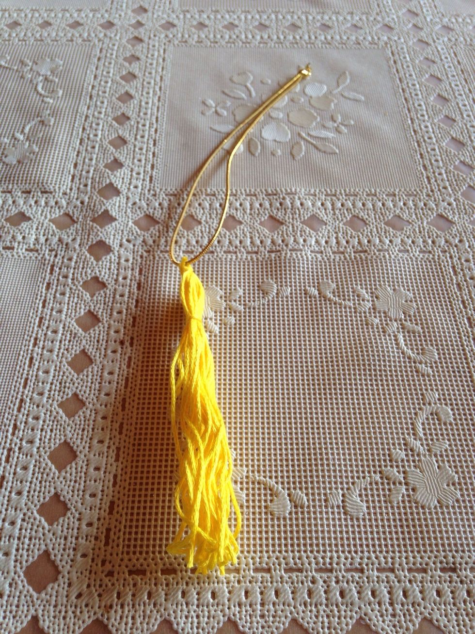 Now to attach the tassel to the hat.   I made this tassel with embroidery floss and a stretchy gold band.