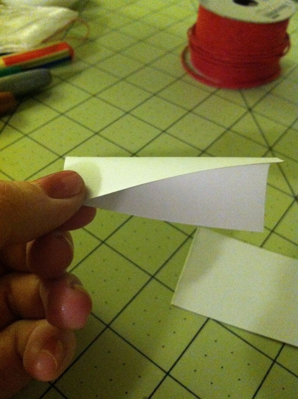 Now, to cut the corners evenly, hold 2 corners together like this so they're lined up but don't fold it completely.