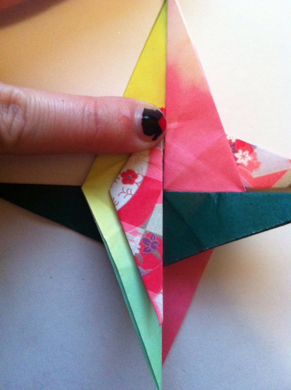 Now to form spiral. Just remember to go counter clockwise. I'm going to identify them by color now to make easier. Fold patterned one down as shown.