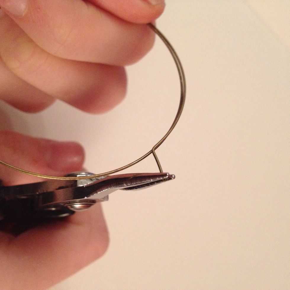 Now to make a loop. Holding your bracelet securely, move your round nose pliers to the very end of the wire, carefully but firmly rotate your pliers so that the wire curls towards the bracelet.