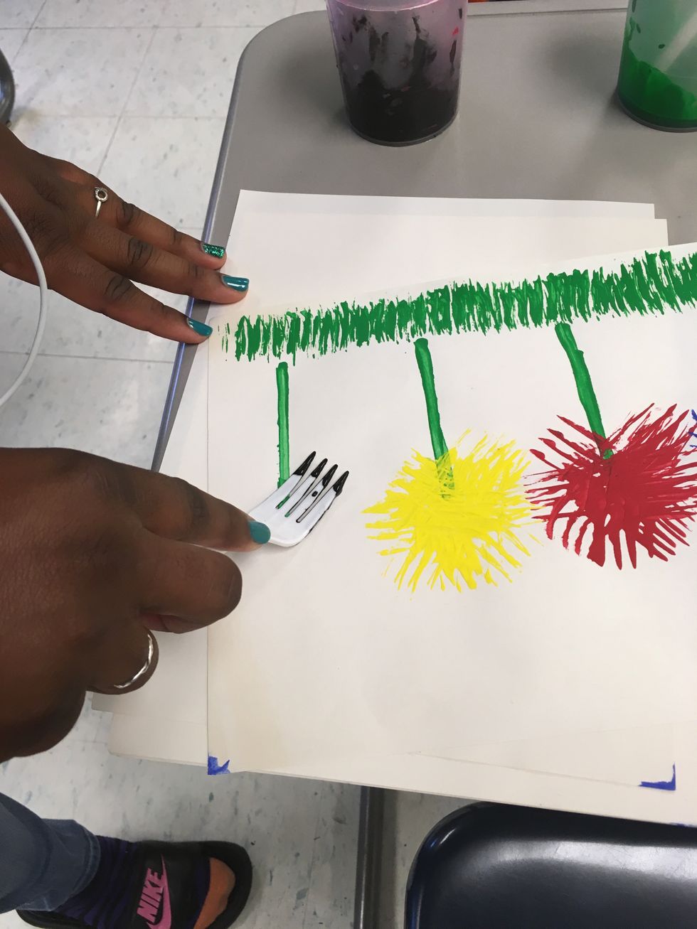 Now to the flower. Take another fork with the color paint desired and press it on the paper at the top of the stem as seen.