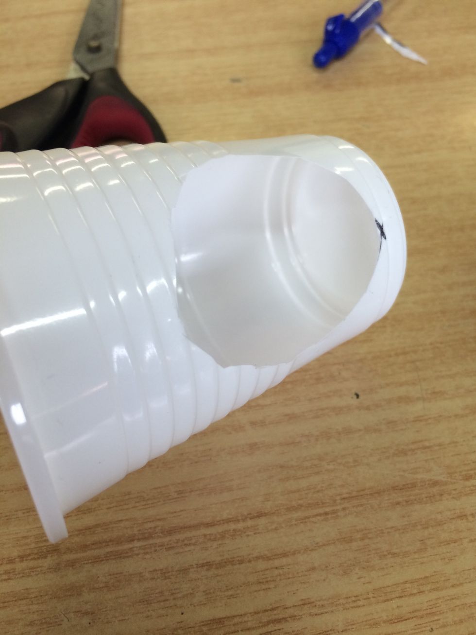 Now trace the size of the toilet paper roll onto the plastic cup with your permanent marker then cut the shape out.