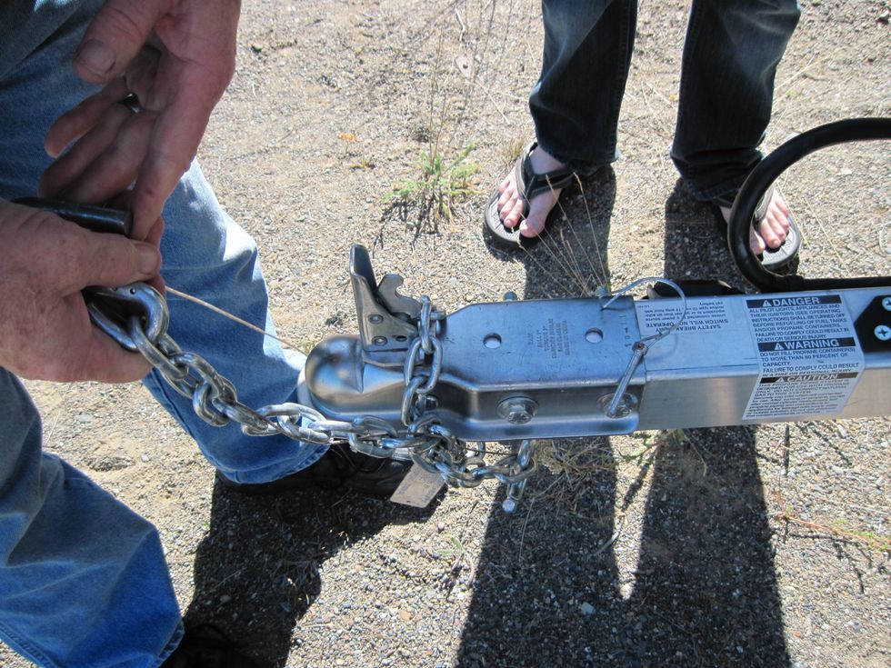 Now unwrap the chains and the little wire. See the pin laying on the tongue of the trailer and that the lever is up.