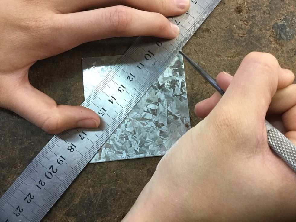 Now use the metal ruler and a scribe to line from corner to corner to find the centre then use a centre punch to make a mark in the middle