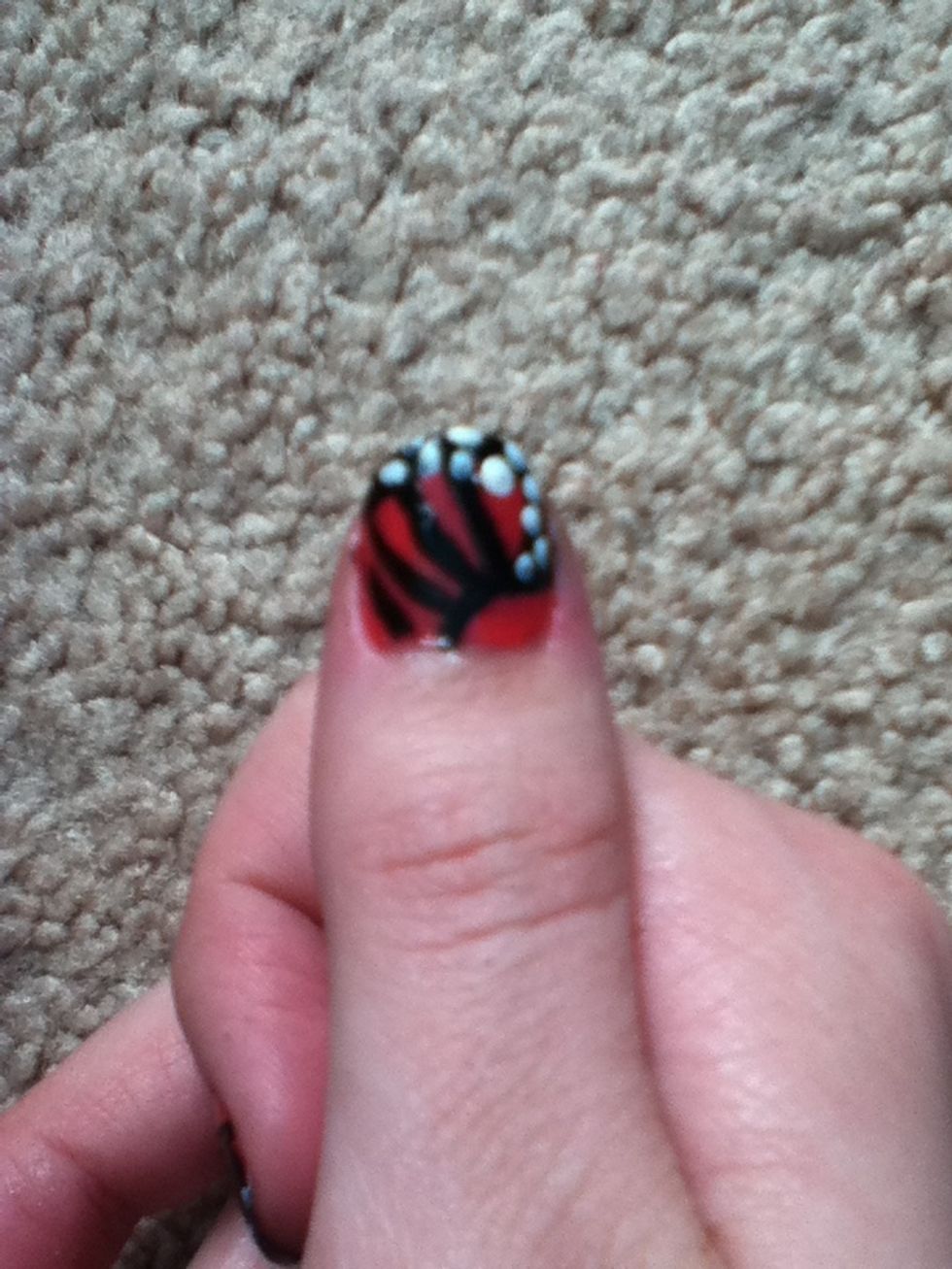 Now using a nail art pen or nail polish in white, add dots to the black part on top and on the sides of the nail, (sort of a poor job but u get the jist.)