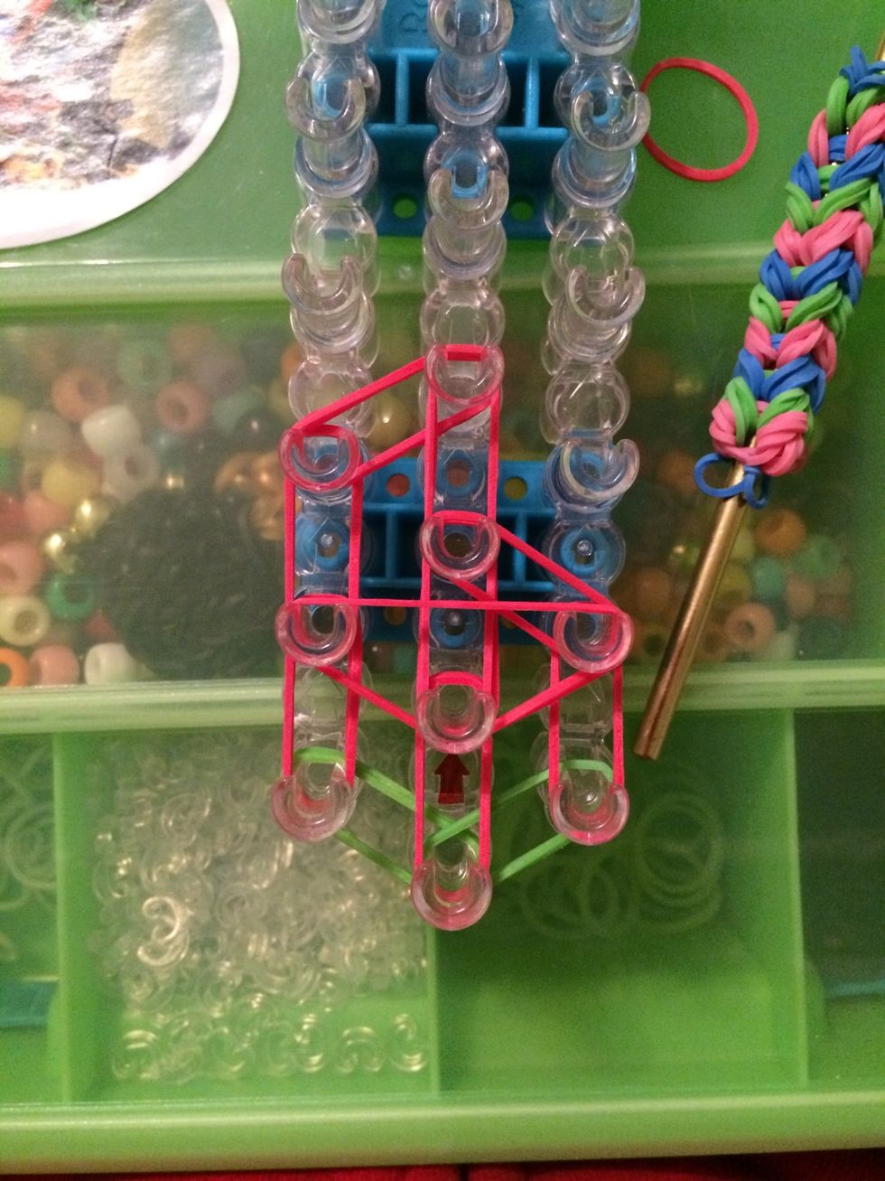 Now we are going to be placing the capping bands. Take 2 red bands and make a triangle over three pegs.