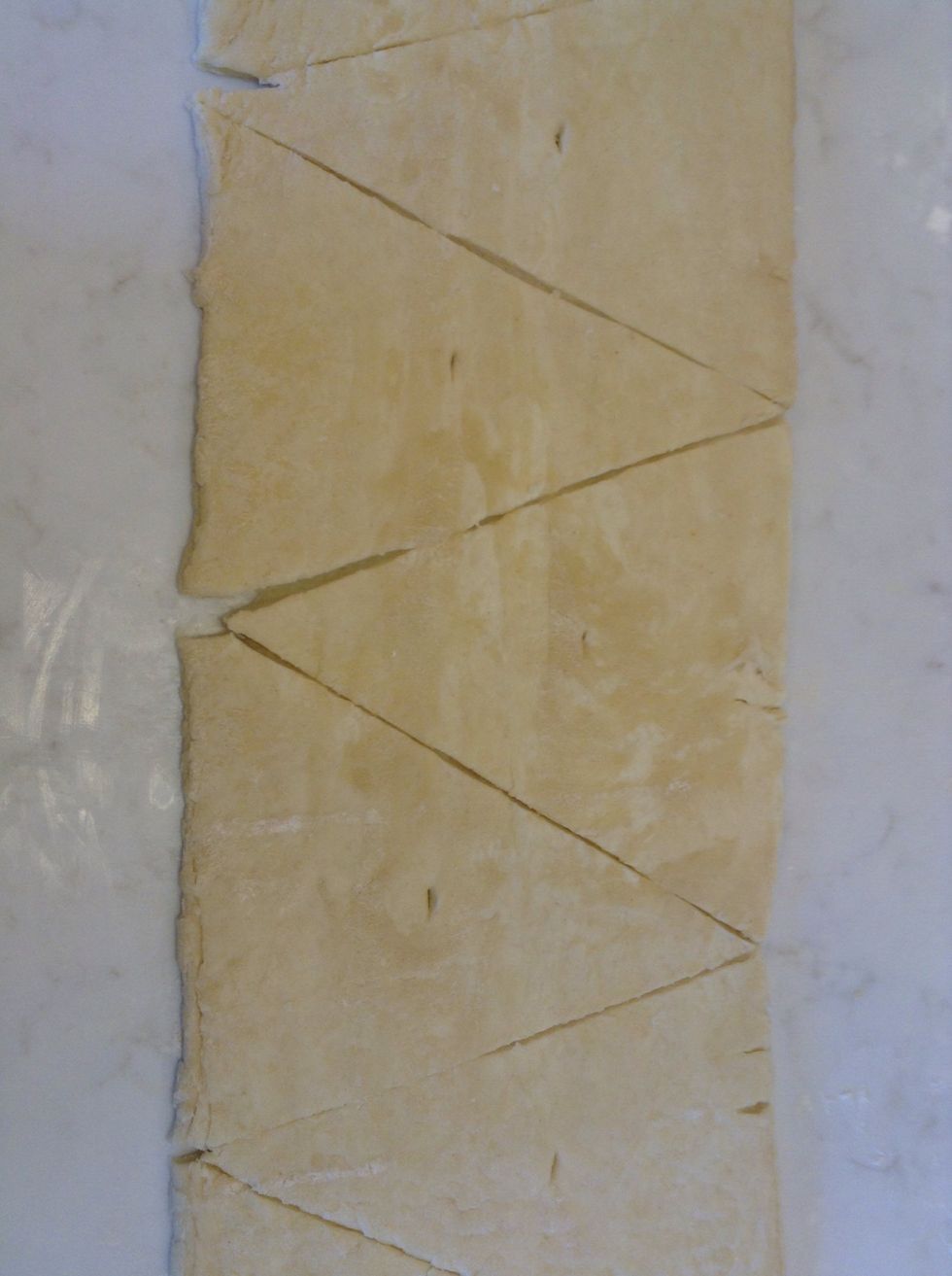 Now we cut the triangle! It has to be in a very uniform way. This is called notching the dough.
