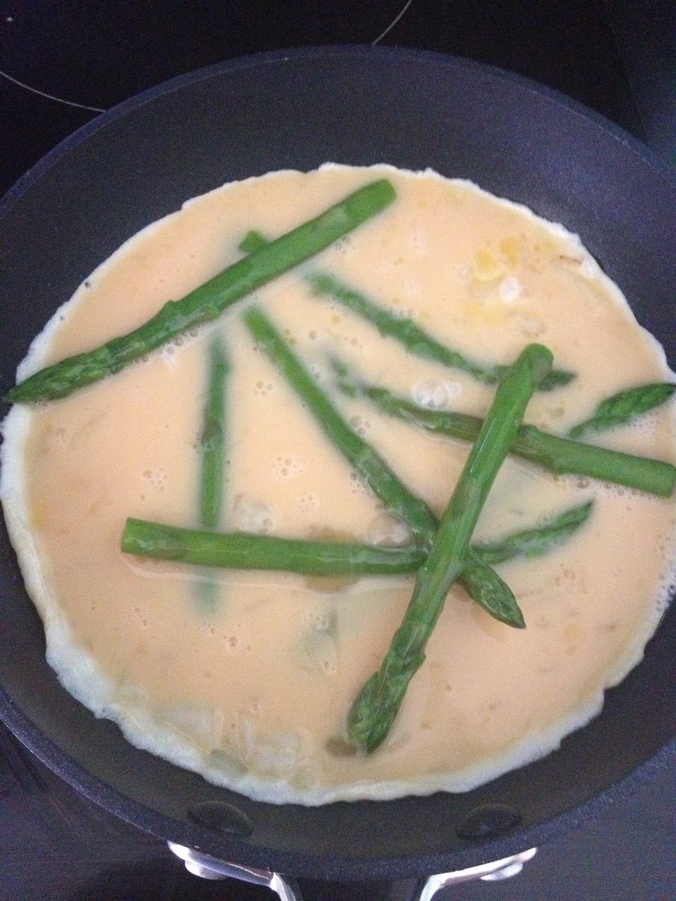 Now you can add the beaten egg. Pour it over the onions and asparagus evenly. It doesn't matter if the egg doesn't cover all of the asparagus, but it does need to reach all sides of the pan.