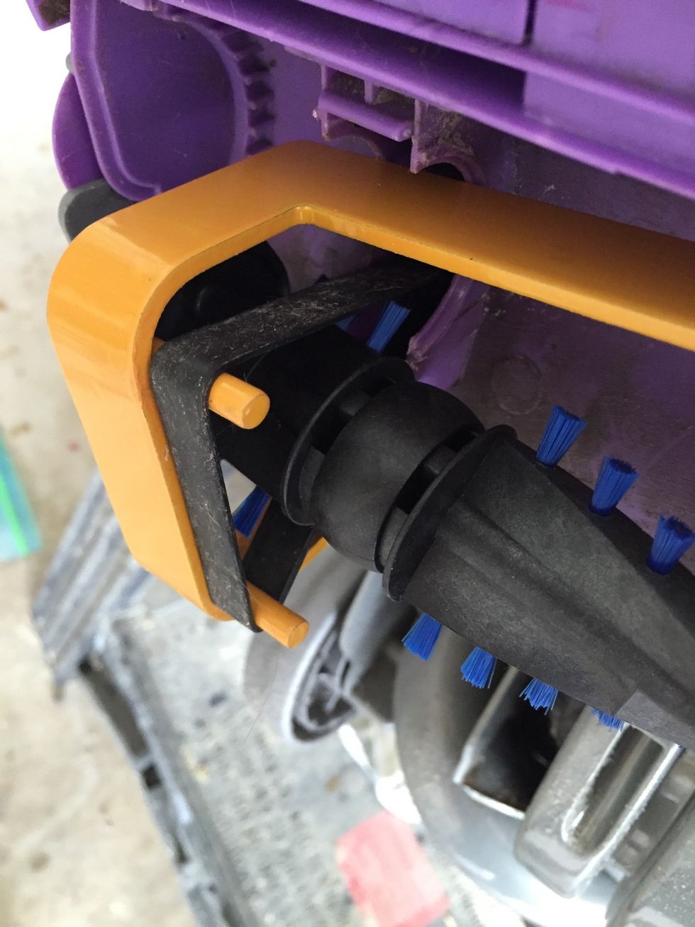 Now you can insert the new beater bar underneath the belt tool and the lifted drive belt. But make sure the end that you're inserting is the one that has the drive belt roller