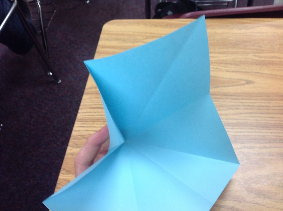 Now you need to open the paper slightly, then push the corner in to meet the points on the top of your fold, and follow the crease line to fold this step.