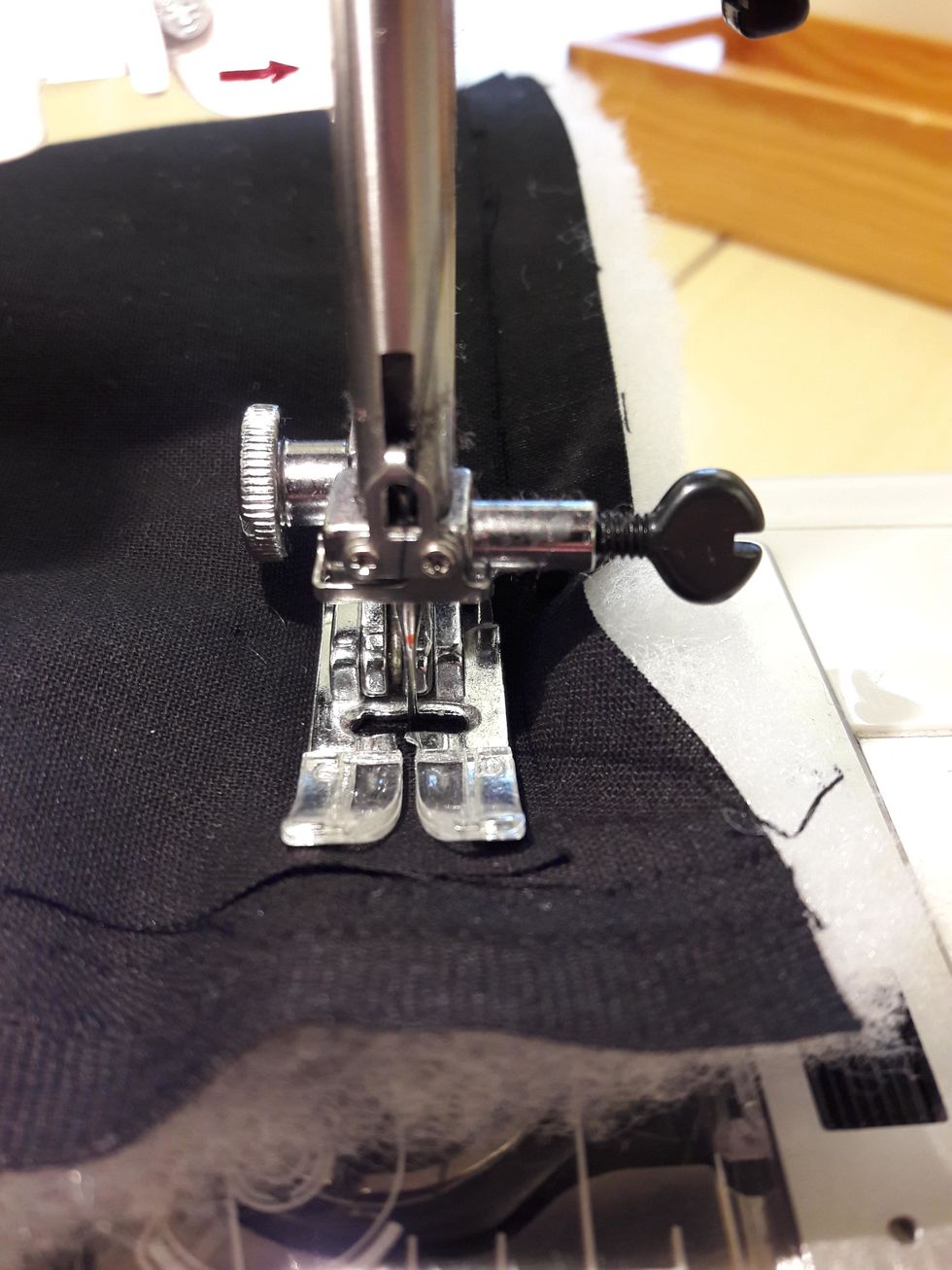 Nu h\u00e5ller n\u00e5len fast tyget s\u00e5 att du kan lyfta pressarfoten och snurra tyget till n\u00e4sta sida.