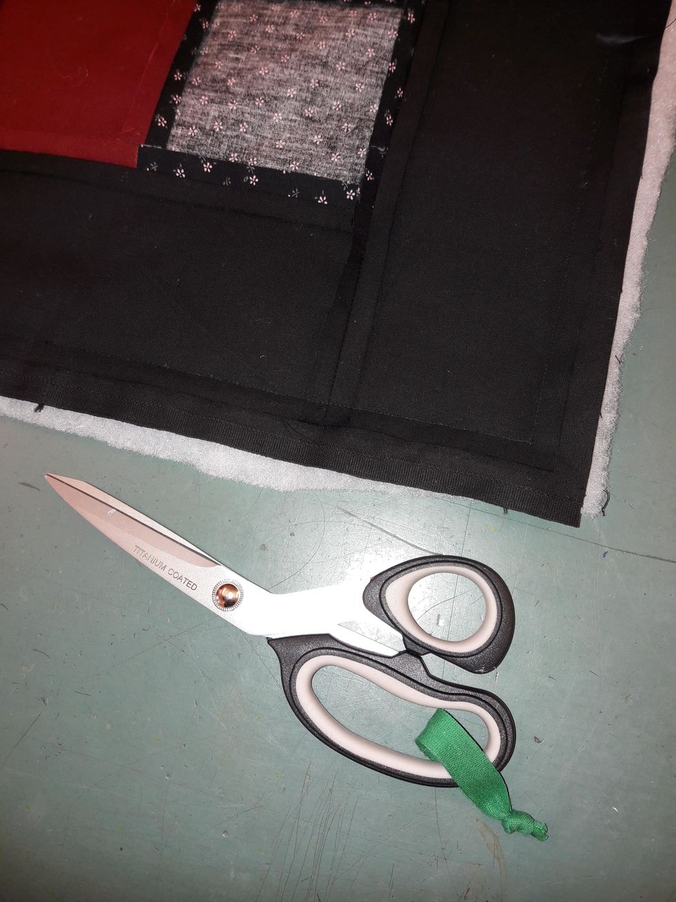 Nu ska du klippa rent kanten. Klipp bort tyget och vadden som sticker ut utanf\u00f6r framstycket. Var f\u00f6rsiktig s\u00e5 att du inte klipper i s\u00f6mmen du just gjorde.