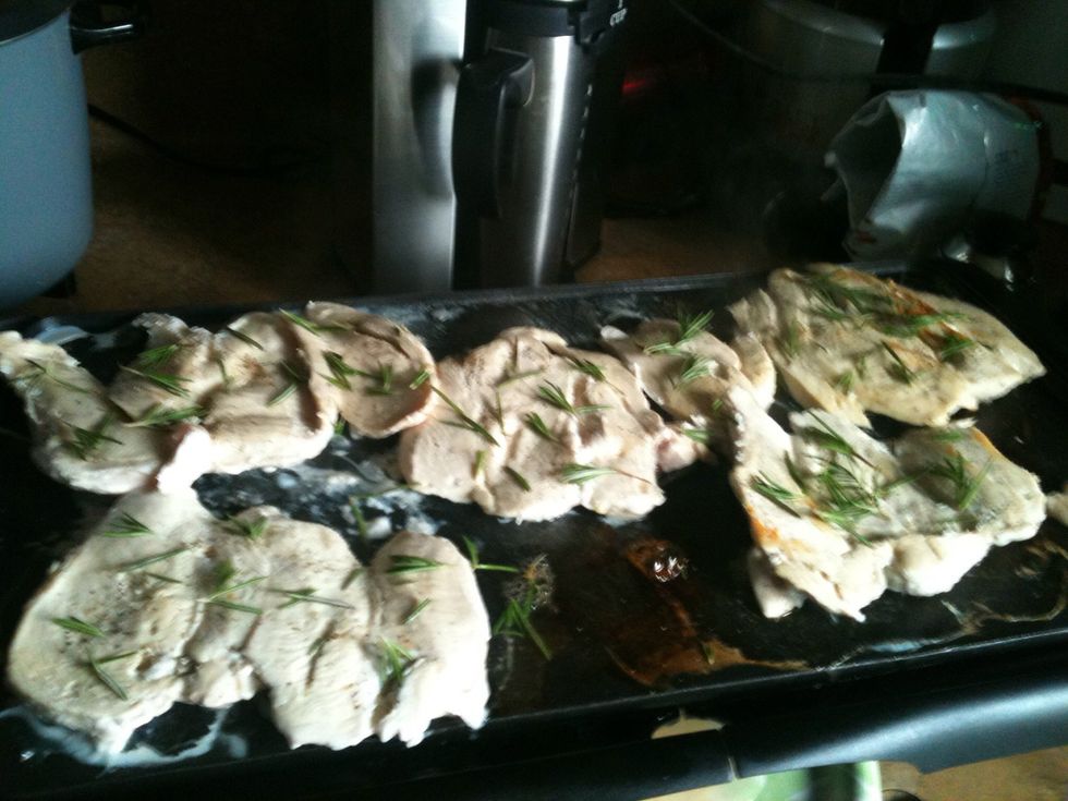 Ok now that our chicken is sizzling, we put rosemary on one side like so! Leave it there for a little.