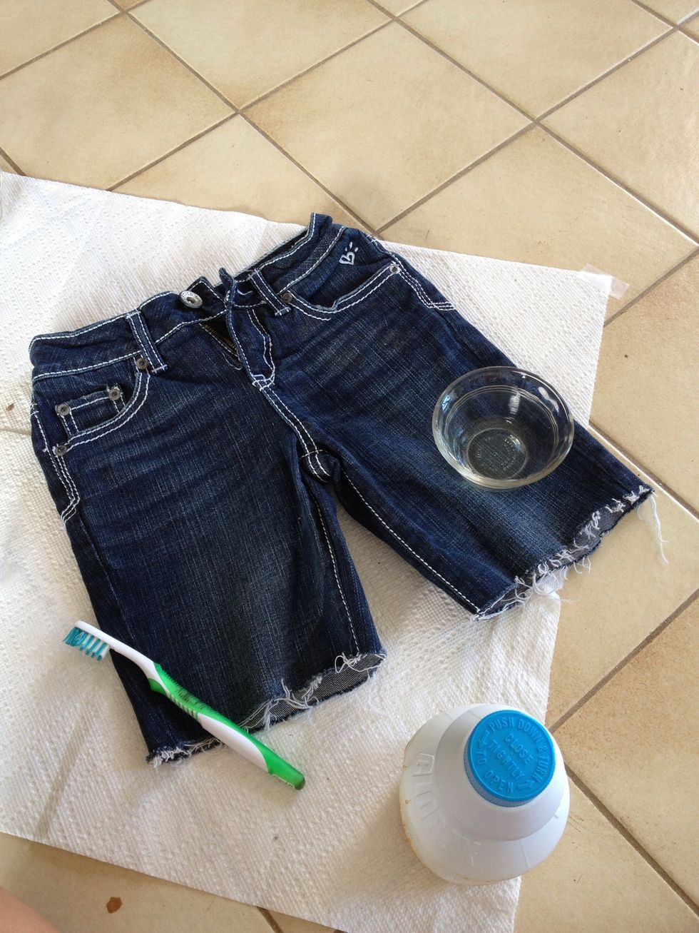 old toothbrush, jean shorts, bleach, cup (or something) and newspaper or paper towel to cover your area