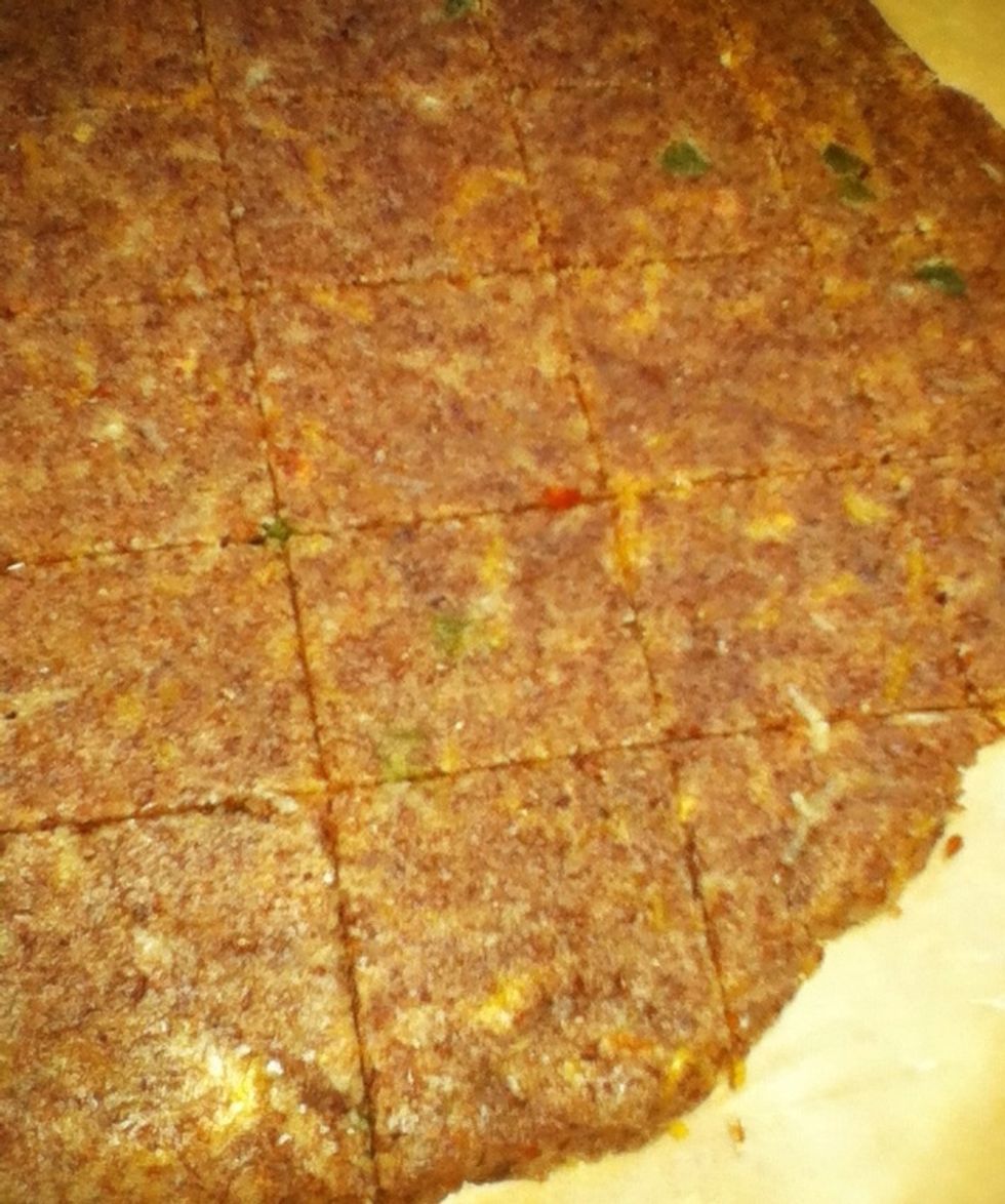 On a baking stone, between two pieces of parchment paper, roll out into rectangle. Try to make same thickness all the way around so it cooks evenly. With sharp knife, score into desired cracker size.